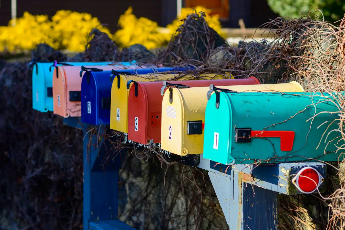 A row of colourful mailboxes next to a hedge